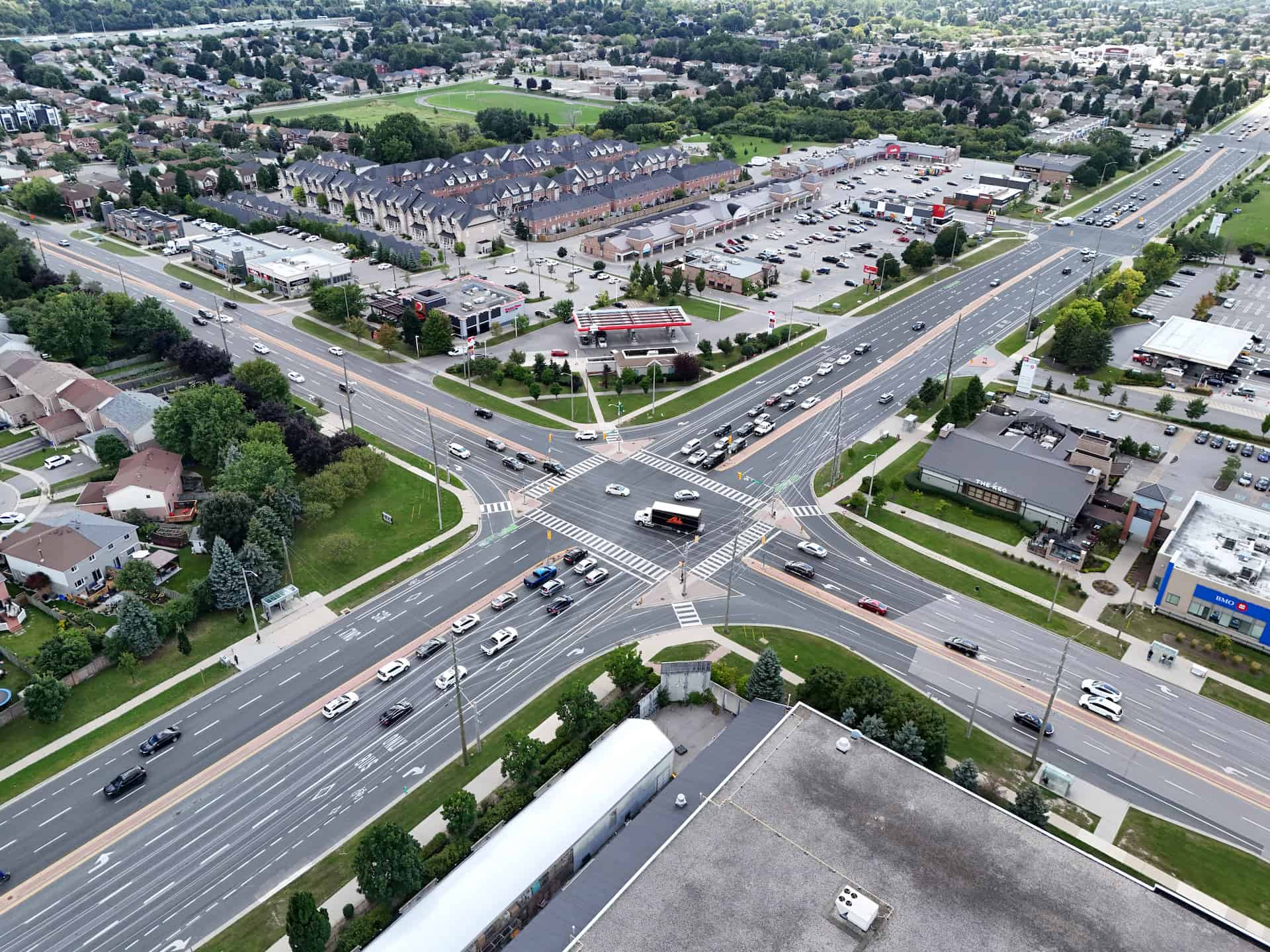 Aerial view of a busy multi-lane junction surrounded by commercial buildings, car parks, and residential areas.