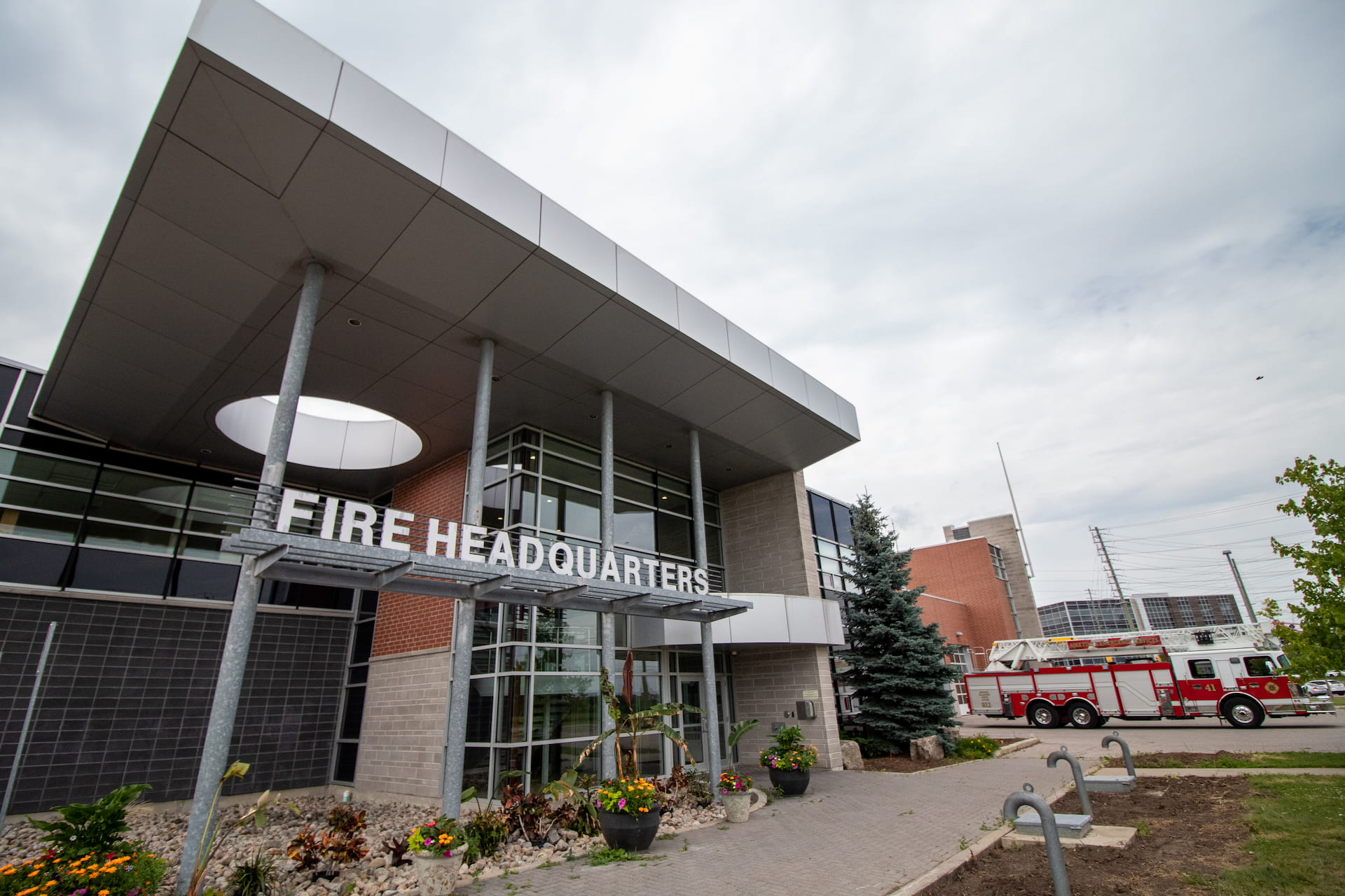 Exterior view of a modern fire headquarters building with a fire engine parked outside.