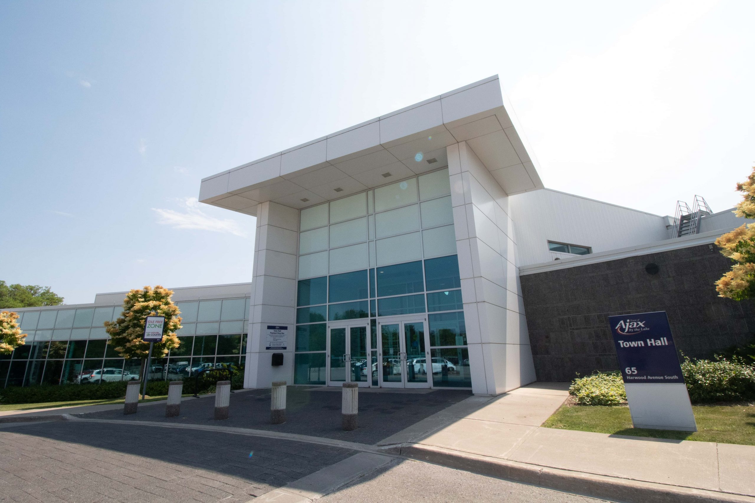 Front entrance of Ajax Town Hall with glass doors, large windows, and a sign displaying the building’s name and address.