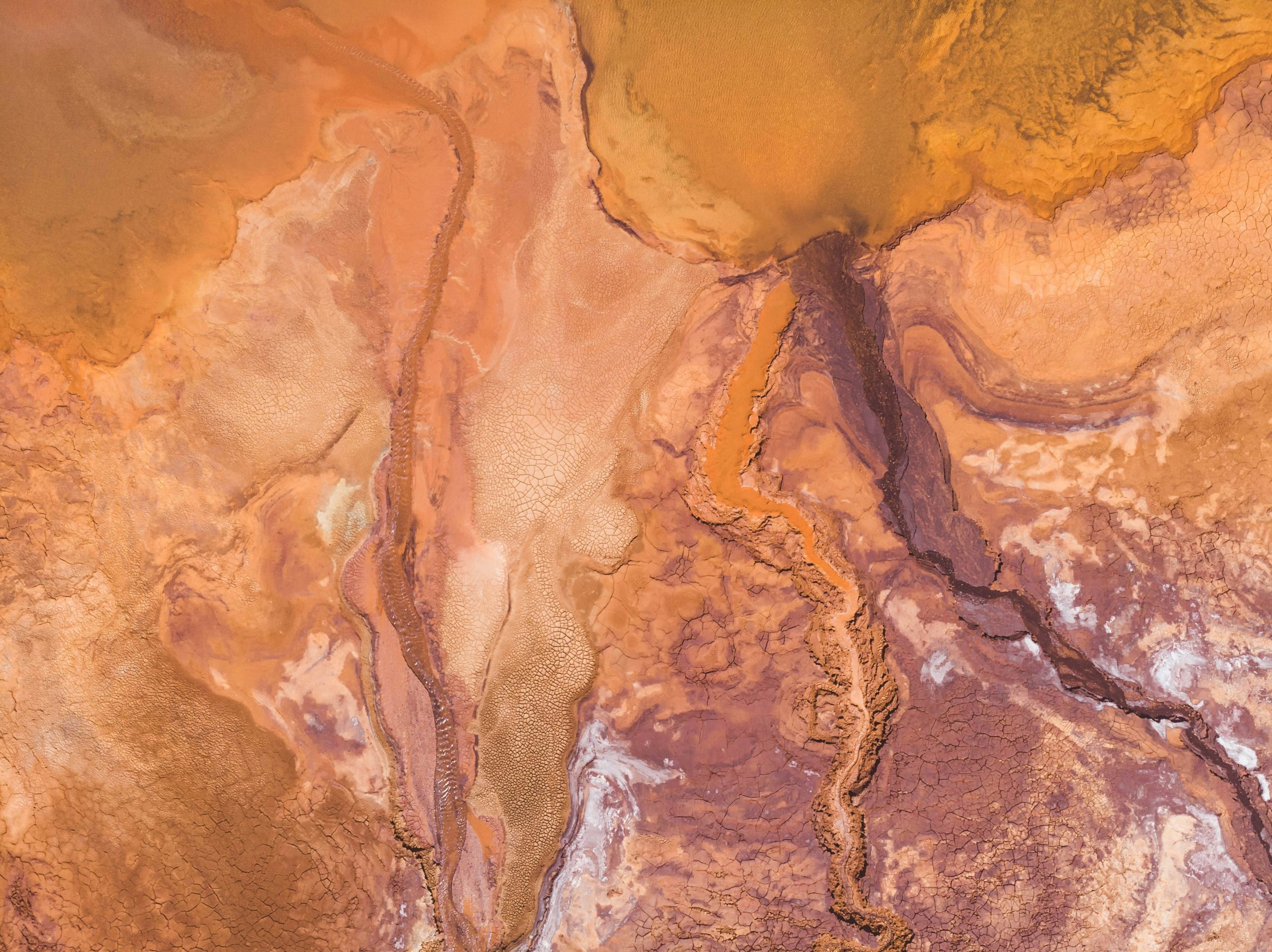 Aerial view of an orange and brown landscape with winding, branching patterns resembling riverbeds.