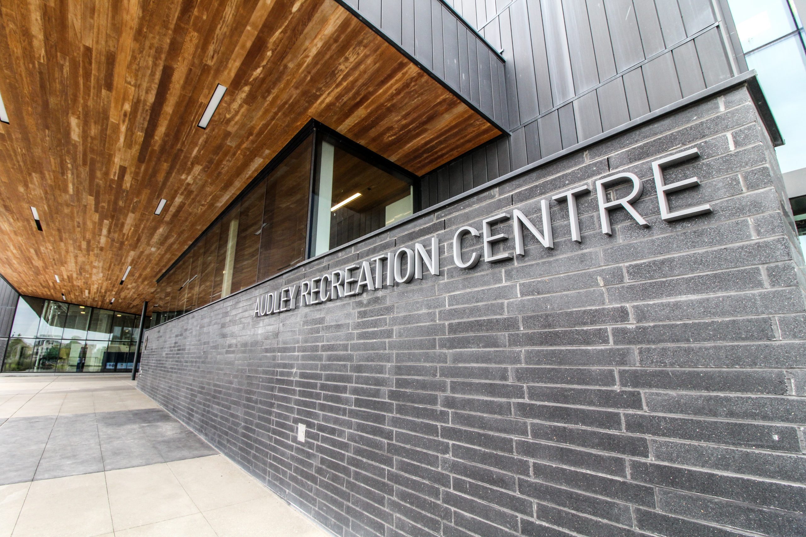 Exterior view of the modern building with a sign reading "Audley Recreation Centre" on a grey brick wall.
