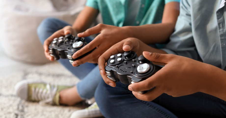 Two people sitting on the floor holding video game controllers, focused on playing a game together.