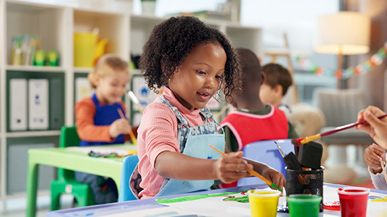 Young children painting with brushes and colourful paints during Preschool programs in a classroom setting.